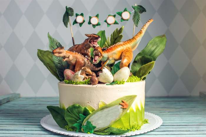 Bánh sinh nhật khủng long cho bé được trang trí bằng tượng hình khủng long trong khu rừng rậm kỷ Jura.