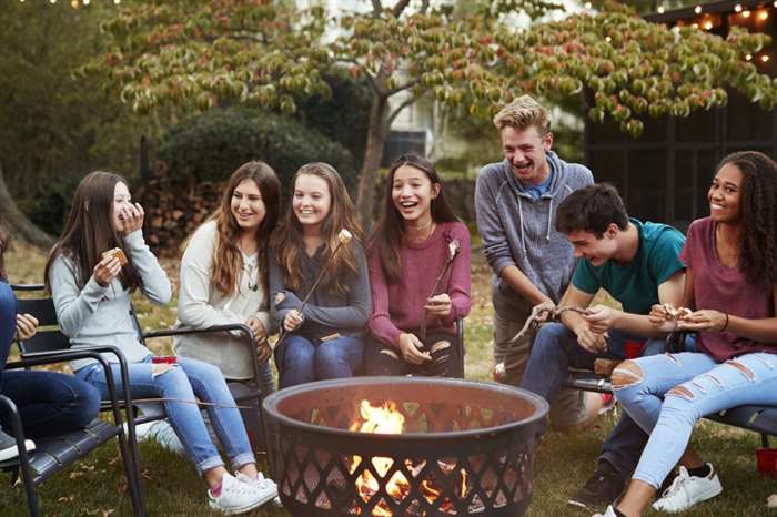 Những người bạn tuổi teen đang ngồi bên đống lửa và nướng những viên kẹo dẻo.
